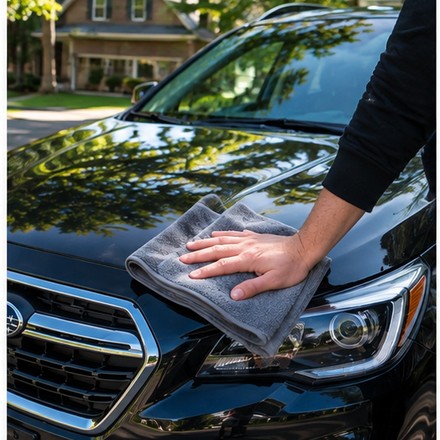 Hand towel-drying a car hood after washing